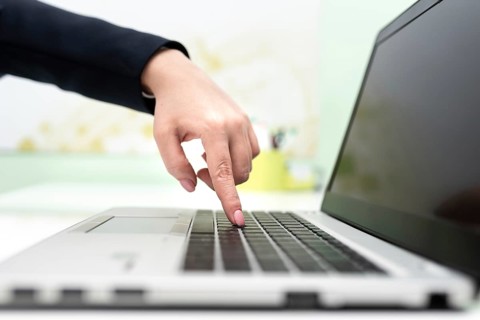 Businesswoman Typing Recent Updates On Lap Top Keyboard On Desk