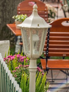 White lantern in the outdoor area of a restaurant with flowers and green furniture, spiekeroog,