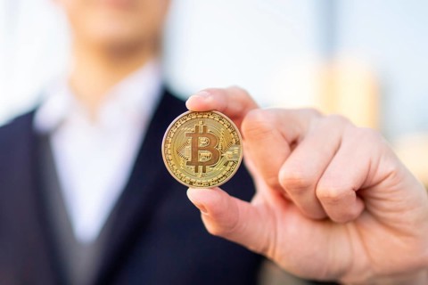 Bitcoin cryptocurrency coin in a young businessman hand. Disruptive blockchain technology concept