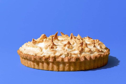 Delicious homemade meringue cake with a lemon flavor filling, minimalist on a blue indigo table.