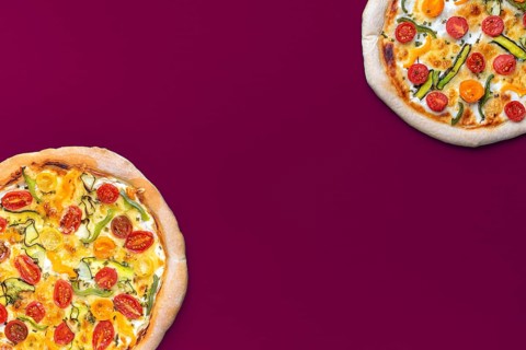 Above view with two homemade pizzas minimalist on a magenta colored table