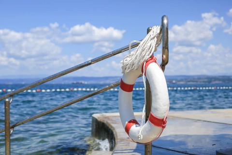 Emergency lifebuoy hanging on fence near sea at beach