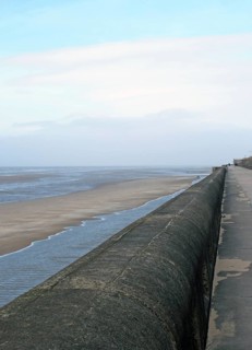 Perspective view of the seawall in blackpool with the beach at low tide in sunlight with the beach