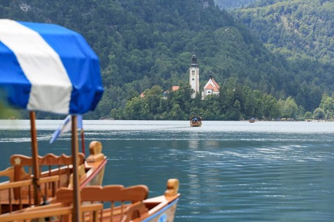 Lake Bled with traditional boat. Beautiful mountain lake in summer with small Church on island with