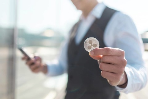 Ripple cryptocurrency coin in a young businessman hand. Disruptive blockchain technology concept