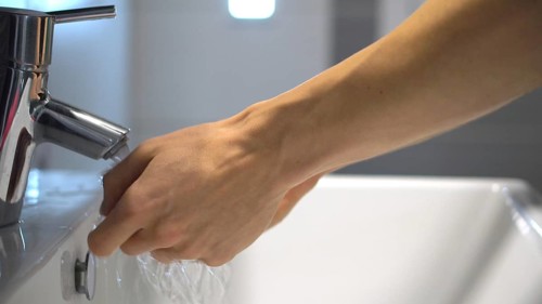 Coronavirus infection prevention. Person washing hands with soap and water, detail