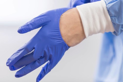 Surgeon doctor in sterile gloves preparing for operation in hospital. He is wearing surgical cap