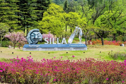 Silla Gyeongju Country Club sign surrounded by colorful flowers and green trees, indicating a