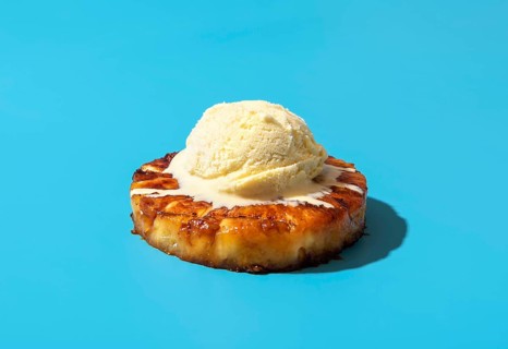 Summer dessert, roasted pineapple ring dipped in rum sauce, with a scoop of vanilla ice cream.