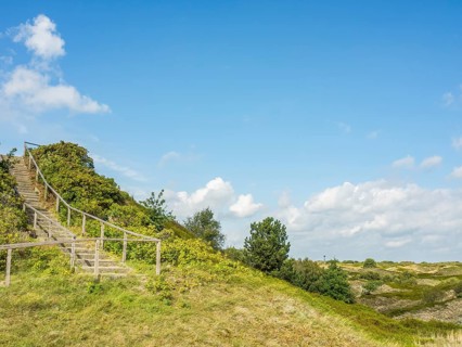 Wooden staircase winds up a green hill under a slightly cloudy sky, spiekeroog, east frisia, north
