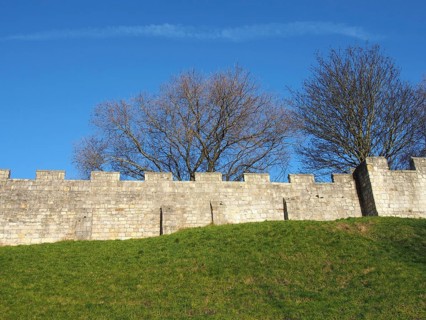 A view of the ancient medieval city walls of york with grass covered embankment and blue sky