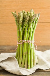 Bunch of green asparagus on wooden table with linen cloth