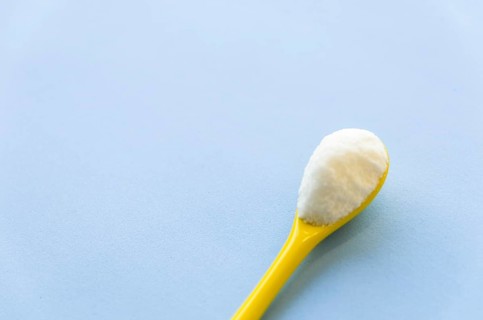 Spoon with sugar close-up on a light blue background