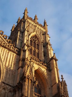 Side view of one of the towers at the front of york minster in sunlight against a blue cloudy sky
