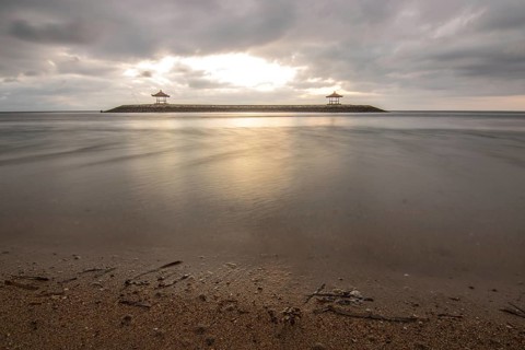 Beautiful seascape in the morning. Tropical sandy beach with breakwater and reflection of the sky