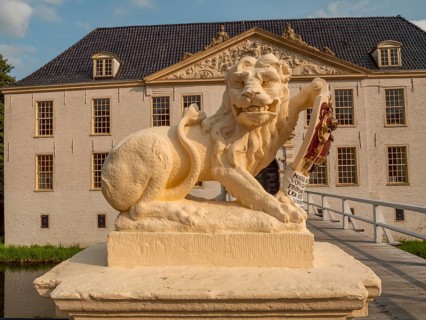 Lion statue with coat of arms in front of a historic building and a bridge, dornum, east frisia,