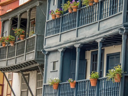 Multi-storey buildings with wooden balustrades and flower pots in front of the windows, la palma,