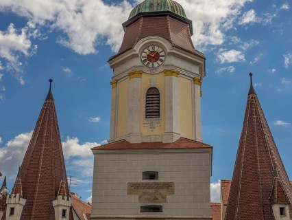 A historic clock tower and church towers against a blue sky with few clouds, Dürnstein, Wachau,