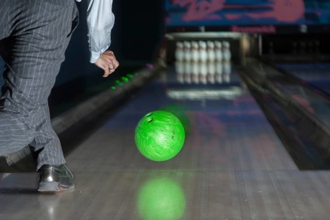 Person throwing a green bowling ball