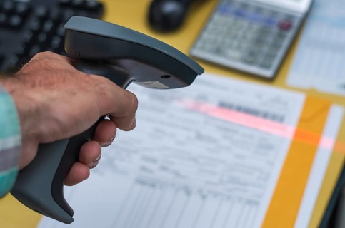 Hand reading the invoice barcode, stored data in the system, making payment
