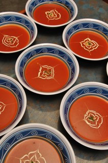 Busy cooks garnish bowls of tomato soup with fresh cream