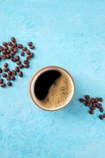 Coffee cup and beans, shot from above on a blue background with a place for text, Food photography