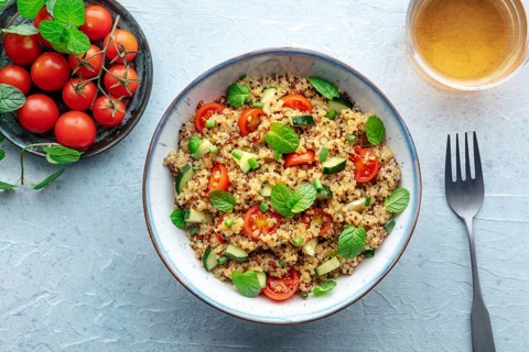 Quinoa tabbouleh salad in a bowl, a healthy dinner with tomatoes and mint, overhead flat lay shot