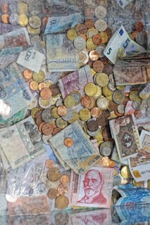 Mix coins and banknotes currency in clear donation money box
