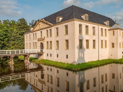 Majestic castle with white facades and blue roofs, perfectly reflected in the surrounding moat,