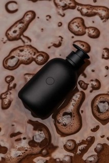 A black bottle surrounded by brown soap bubbles and foam, AI generated
