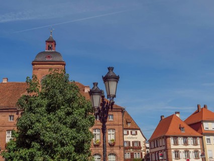 Historic buildings with red tiled roofs next to lanterns and trees under a clear sky, Weissenburg,