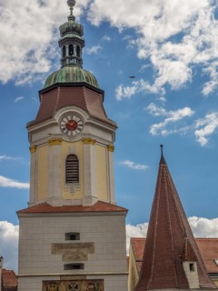 A towering clock tower and a steep church spire against a cloudy sky, Dürnstein, Wachau, Danube,