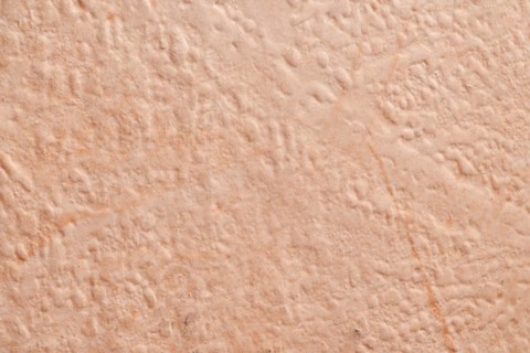 Light beige, roughly plastered house wall as full-format background