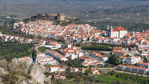Woman viewing Castelo de Vide from a rock in Alentejo, Portugal from Serra de Sao Mamede mountains