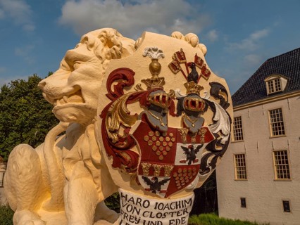 Detailed view of a lion statue with coat of arms, building in the background, dornum, east frisia,