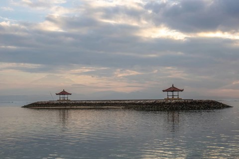 Beautiful seascape in the morning. Tropical sandy beach with breakwater and reflection of the sky