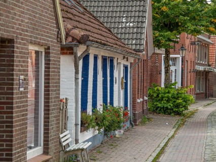 Street with traditional old houses made of brick and wood, decorated with flowers, dornum, east