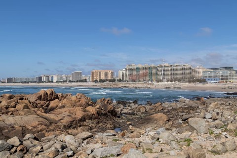 Rock in front of city view with sandy beach and surf in the Atlantic Ocean, landmark She Changes,
