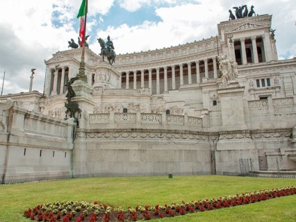 Side view of the Altar of the Nation in Rome with Italian flag and manicured lawn, rome, italy