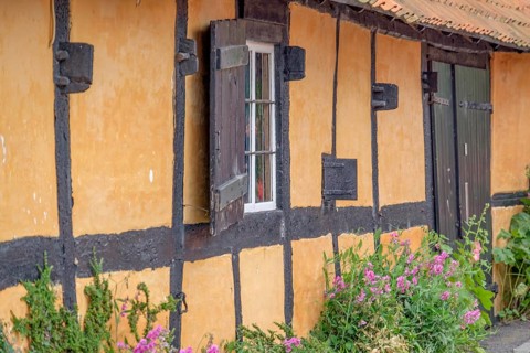 Rustic half-timbered house with colourful flowers in the foreground and striking black beams,