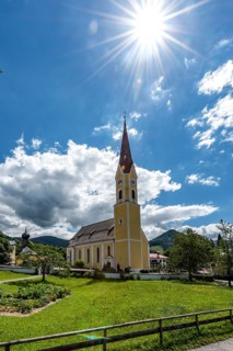 Church at Schliersee in Bavaria Germany with sun and blue sky in front of wooded mountains