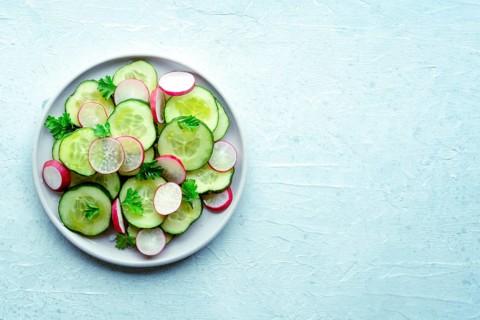 Fresh cucumber and radish salad with parsley, overhead flat lay shot. Simple vegan recipe on a