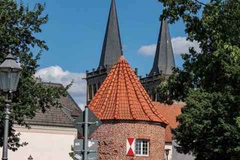 Historic brick building with striking towers and trees under a blue-green sky, Xanten, Lower Rhine,