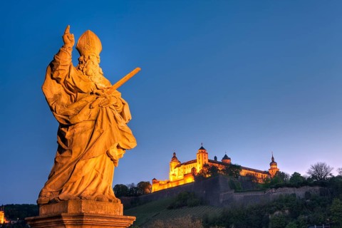 Figure of a saint on the Old Main Bridge with a view of Marienberg Fortress, Wuerzburg, Lower