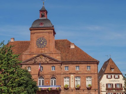 Building with historic façade, a clock and shutters under a clear sky, Weissenburg, Alsace, France,