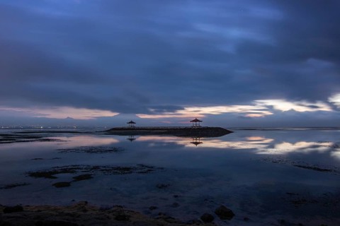 Beautiful seascape in the morning. Tropical sandy beach with breakwater and reflection of the sky