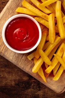 French fries, potato snack with ketchup, fast food on a wooden table, shot from the top with a