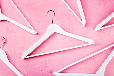 Fashion collection concept. White wooden hangers, a flat lay layout on pink. Shopping background,