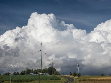 Road between Töpen and Mödlareuth with wind turbines and massive clouds behind them