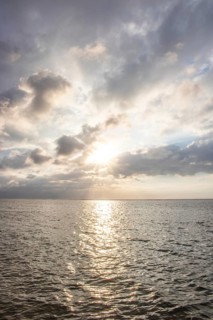 Beautiful seascape in the morning. Tropical sandy beach with breakwater and reflection of the sky